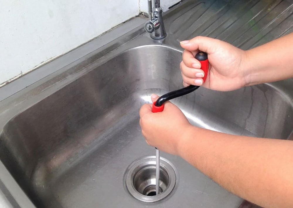 plumber-using-a-drain-auger-snake How to Fix a Gurgling Kitchen Sink Easily