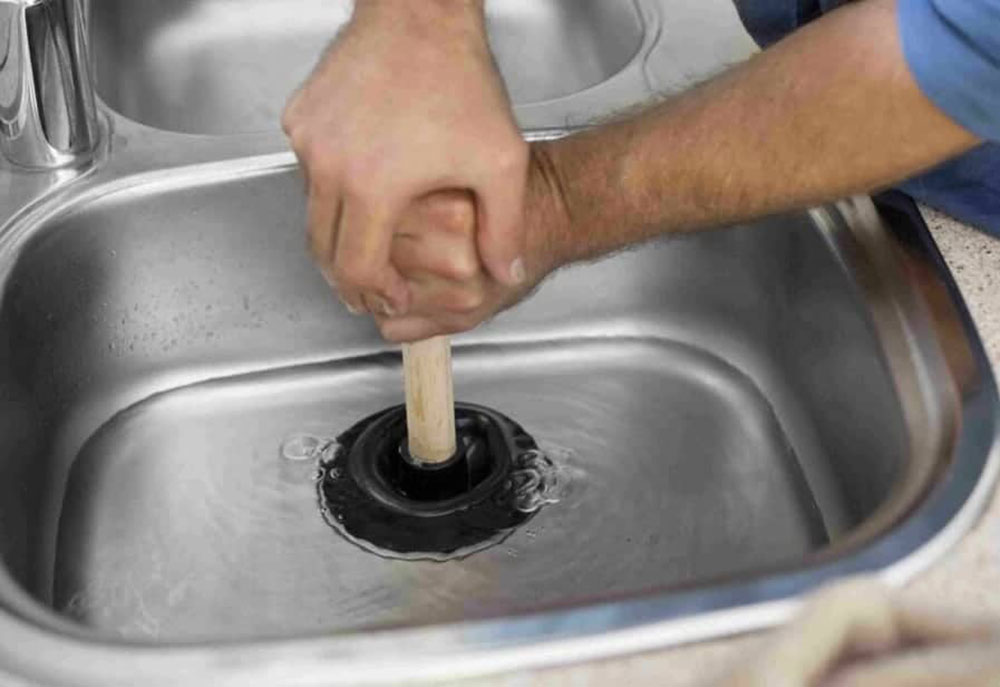 plumber-using-a-plunger-to-unclog-a-sink How to Unclog a Double Kitchen Sink Easily